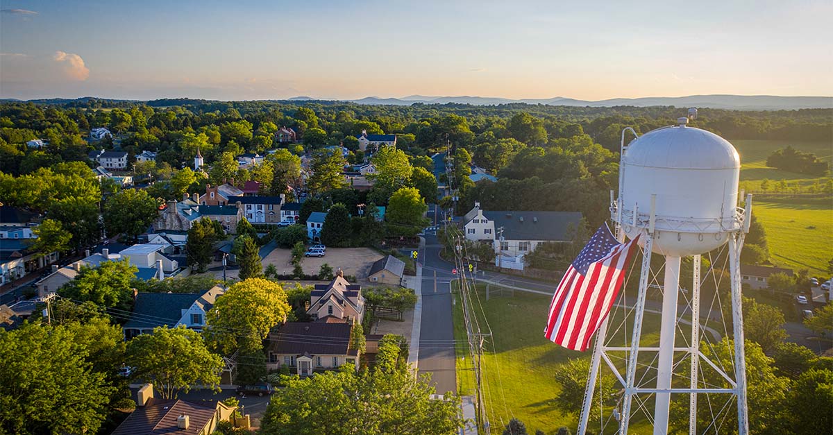 A small rural town with a water tower and American flag, symbolizing community and rural healthcare transformation.