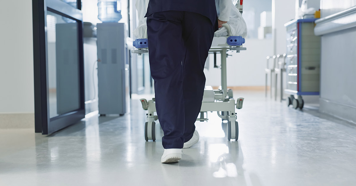 Nurse pushing a patient on a gurney through a hospital corridor representing patient transfers at an academic medical center