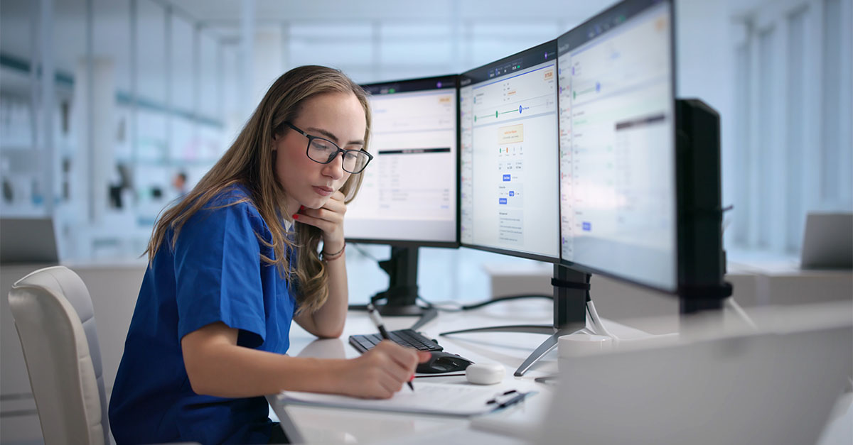 Healthcare provider reviewing patient information on multiple monitors, representing Medicare ACCESS Payment Model billing and co-management services